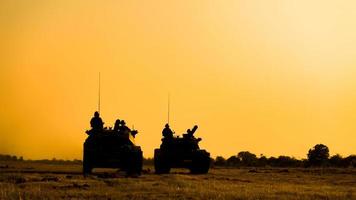 sagome di soldati dell'esercito nella nebbia contro un tramonto, squadra di marines in azione, circondato da fuoco e fumo, sparando con fucile d'assalto e mitragliatrice, attaccando il nemico foto