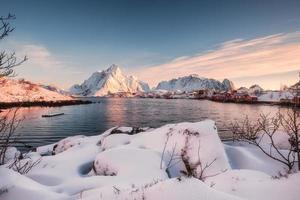 villaggio scandinavo con mucchio nevoso sulla costa all'alba foto