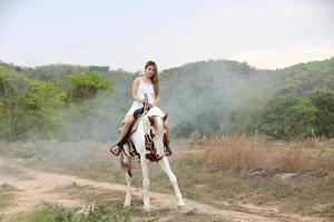 giovane donna con il suo cavallo nella luce del tramonto di sera. fotografia all'aperto con ragazza modella. umore dello stile di vita foto