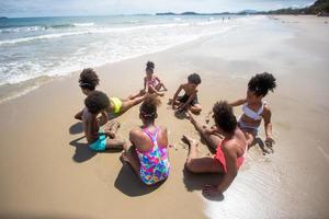 bambini che giocano a correre sulla sabbia in spiaggia foto