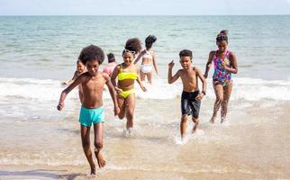 bambini che giocano a correre sulla sabbia in spiaggia foto