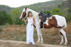 giovane donna con il suo cavallo nella luce del tramonto di sera. fotografia all'aperto con ragazza modella. umore dello stile di vita foto