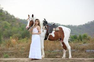 giovane donna con il suo cavallo nella luce del tramonto di sera. fotografia all'aperto con ragazza modella. umore dello stile di vita foto