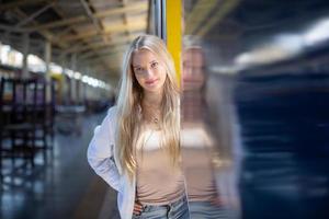 ritratto di una bella giovane donna bionda in piedi in treno. foto