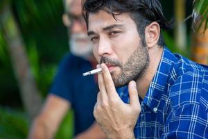 un ritratto di un figlio adulto hipster che fuma e un padre anziano trascorrono del tempo insieme nel fine settimana a casa. foto