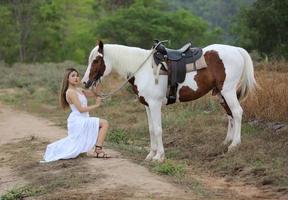 giovane donna con il suo cavallo nella luce del tramonto di sera. fotografia all'aperto con ragazza modella. umore dello stile di vita foto