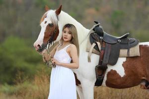 giovane donna con il suo cavallo nella luce del tramonto di sera. fotografia all'aperto con ragazza modella. umore dello stile di vita foto