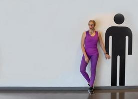 ritratto di donne con abbigliamento sportivo in piedi accanto al personaggio grafico degli uomini contro il muro bianco