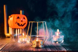 concetto di vacanza di Halloween di zucca, candele, decorazioni spettrali con fumo di tono verde intorno su un tavolo di legno scuro, primo piano. foto