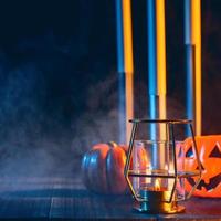 concetto di vacanza di Halloween di zucca, candele, decorazioni spettrali con fumo di tono blu intorno su un tavolo di legno scuro, primo piano. foto