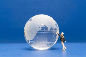 persone in miniatura adolescente spruzzando vernice globo cristallino su sfondo blu foto