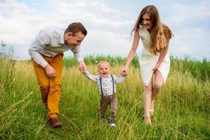 padre e madre guidano per mano il figlio di un anno. foto