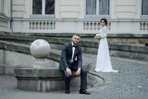 sposi in posa nella città antica. giovane sposa carina con un mazzo di fiori e l'abbraccio dello sposo. foto