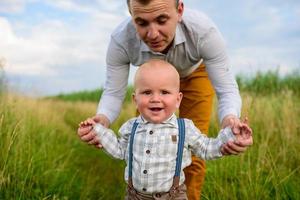 padre e madre guidano per mano il figlio di un anno. foto