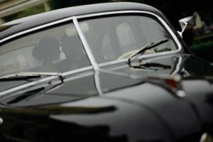 bella giovane sposa e sposo felici che guardano dall'auto retrò foto