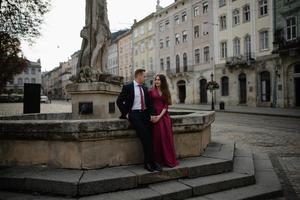 ritratto di bella coppia sorridente di amore seduta vicino alla fontana all'aperto in città. bel giovane e donna. foto