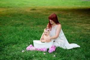 la mamma aiuta la figlia di un anno a fare il bagno in bagno. girato in un parco all'aperto nella natura. foto