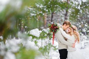 gli sposi sono seduti sul tronco nella foresta d'inverno. avvicinamento. cerimonia di nozze d'inverno. foto