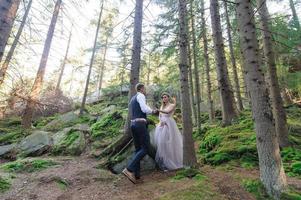 una coppia di sposini attraenti, un momento felice e gioioso. un uomo e una donna si radono e si baciano in abiti da festa. cerimonia nuziale in stile bohémien nella foresta all'aria aperta. foto
