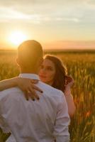 sposi in un campo di grano. la coppia si abbraccia durante il tramonto foto