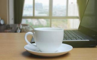 tazza di caffè sul pavimento di legno e sullo sfondo sfocato della finestra della camera da letto foto