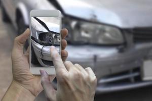mano che tiene lo smartphone scatta una foto sulla scena di un incidente d'auto, incidente d'auto per l'assicurazione
