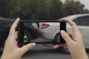 mano che tiene lo smartphone scatta una foto sulla scena di un incidente d'auto, incidente d'auto per l'assicurazione