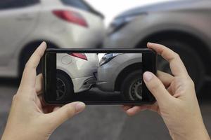 mano che tiene lo smartphone scatta una foto sulla scena di un incidente d'auto, incidente d'auto per l'assicurazione