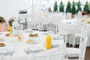 tavoli da pranzo rotondi ricoperti di stoffa blu stanno in un padiglione bianco per matrimoni foto