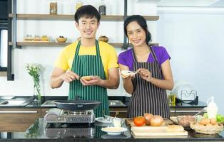 le coppie romantiche e adorabili asiatiche si divertono e cucinano felicemente il cibo in cucina foto