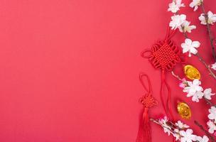 concetto di design del capodanno lunare cinese - bellissimo nodo cinese con fiore di prugna isolato su sfondo rosso, disposizione piatta, vista dall'alto, disposizione aerea. foto