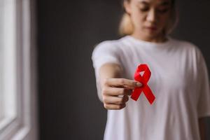 donna che tiene il nastro rosso per la campagna contro il cancro al seno foto