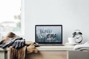 concetto di sfondo invernale con iscrizione dell'ora invernale sullo schermo del laptop foto