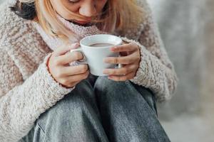 una ragazza con abiti invernali che si gode una tazza di bevanda calda nella stagione invernale a casa foto