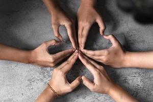 l'amore plasmato dalle mani delle persone in un gruppo di persone diverse collegate tra loro come simbolo di supporto che esprime la sensazione di lavoro di squadra e di stare insieme foto