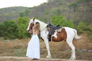 giovane donna con il suo cavallo nella luce del tramonto di sera. fotografia all'aperto con ragazza modella. umore dello stile di vita foto