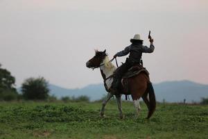 cowboy a cavallo con la mano che tiene la pistola contro lo sfondo del tramonto. foto