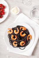 pasta italiana nera con cibo di gamberi su sfondo chiaro foto