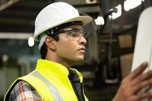 il caposquadra o il lavoratore lavorano in fabbrica controllano la macchina o i prodotti in loco. ingegnere o tecnico che controlla materiale o macchina sull'impianto. industriale e di fabbrica. foto