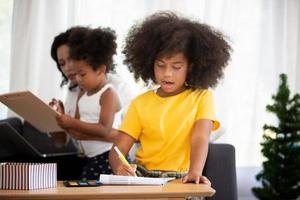 ritratto di felice giovane famiglia afroamericana con bambini piccoli sedersi rilassarsi sul divano coccole, sorridente genitori neri riposano sul divano abbraccio bambini in età prescolare che posano per una foto a casa insieme