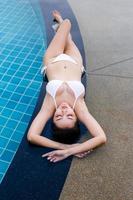 giovane donna godendo e rilassante a bordo piscina. modello di ragazza snella in bikini bianco a bordo piscina. foto