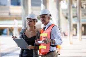 l'ingegnere e la donna d'affari che controllano gli appunti al cantiere edile. il concetto di ingegneria, costruzione, vita cittadina e futuro. foto