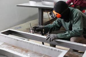 saldatore usato mola su acciaio in fabbrica con scintille, processo di saldatura presso l'officina industriale, mani con strumento nel telaio. foto