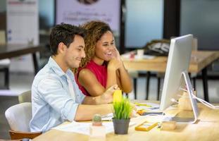 diversi colleghi di lavoro seduti a una scrivania in un ufficio moderno che parlano insieme su un computer. foto