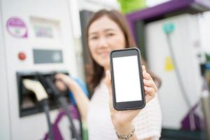 schermo vuoto dello smartphone mockup isolato con tracciato di ritaglio. giovane donna asiatica che utilizza l'applicazione di ricarica ev sullo smartphone si connette con la stazione di ricarica, bev o stazione di ricarica per veicoli elettrici foto