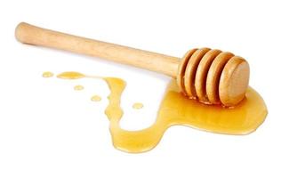 miele che scorre da un bastoncino di legno foto