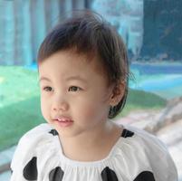 Ragazza asiatica carina di 3 anni, bambino piccolo che guarda a sinistra con la faccia sorridente. foto