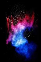 nuvola di esplosione di polvere blu rossa su sfondo nero. spruzzata di particelle di polvere blu lanciata. foto