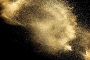 esplosione di sabbia isolata su sfondo nero. congelare il movimento di schizzi di polvere sabbiosa. foto