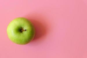 un frutto di mela verde maturo isolato su sfondo rosa con copia spazio per il testo. vista dall'alto. foto